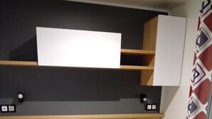 Ein Schlafzimmer mit einem Bett, einem Holzkopfteil, eingebauten Regalen und einer Wandleuchte.