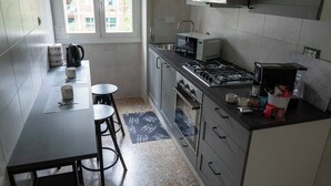 Une cuisine compacte équipée d’une cuisinière à gaz, d’un four à micro-ondes et d’une fenêtre donnant sur des immeubles.