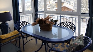 A balcony with a table and chairs, a lamp, and a view of a snowy landscape.
