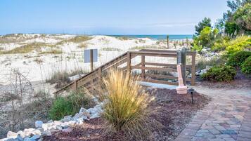 A wooden deck with a metal railing overlooking a beach.