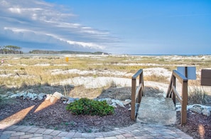 A pathway leading to a beach with a wooden boardwalk, a small bush, and a distant view of the ocean. - 2BR/2B Oceanfront & Inlet View Gated w/pool (North Myrtle Beach)