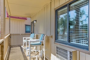 A balcony with two white chairs and a table, a window with blinds, and a door with a light fixture. - 2BR/2B Oceanfront & Inlet View Gated w/pool (North Myrtle Beach)