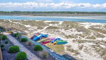 A beach with kayaks and a wooden walkway leading to a building.