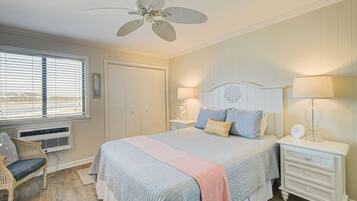 A bedroom with a bed, nightstands, a chair, a ceiling fan, and a window with blinds.
