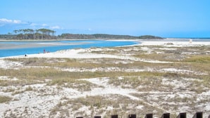 Ein Strand mit Dünen und blauem Himmel.