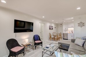 A living room with a flat-screen TV, wicker chairs, a glass coffee table, and a sofa. - Inlet Facing 1st Floor 2B/2B Condo w/pool (North Myrtle Beach)