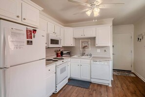 A compact kitchen with white cabinetry, a microwave, a stove, a sink, and a ceiling fan. - Inlet Point Villas Oceanfront Gated 2B/2B w/pool (North Myrtle Beach)