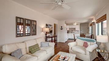 A living room with a white sofa, a coffee table, and a ceiling fan.