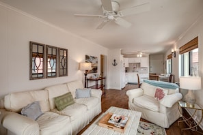 Ein Wohnzimmer mit einem weißen Sofa, einem Couchtisch und einem Deckenventilator.