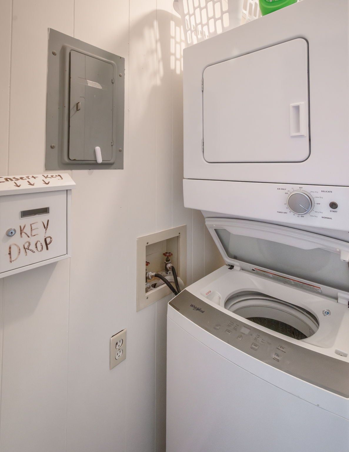 Une buanderie équipée d’un lave-linge et d’un sèche-linge à chargement frontal, d’un panneau électrique et d’un espace pour déposer les clés.