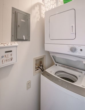 Une buanderie équipée d’un lave-linge et d’un sèche-linge à chargement frontal, d’un panneau électrique et d’un espace pour déposer les clés.
