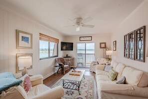 Ein Wohnzimmer mit Sofa, Couchtisch, Fernseher und Blick ins Freie.
