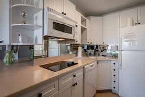 Eine Küche mit weißen Schränken, einer Mikrowelle, einem Herd und einem Kühlschrank.
