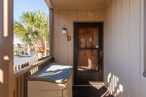 Een hotelkamer met een balkon, een deur en uitzicht op palmbomen en een straat.