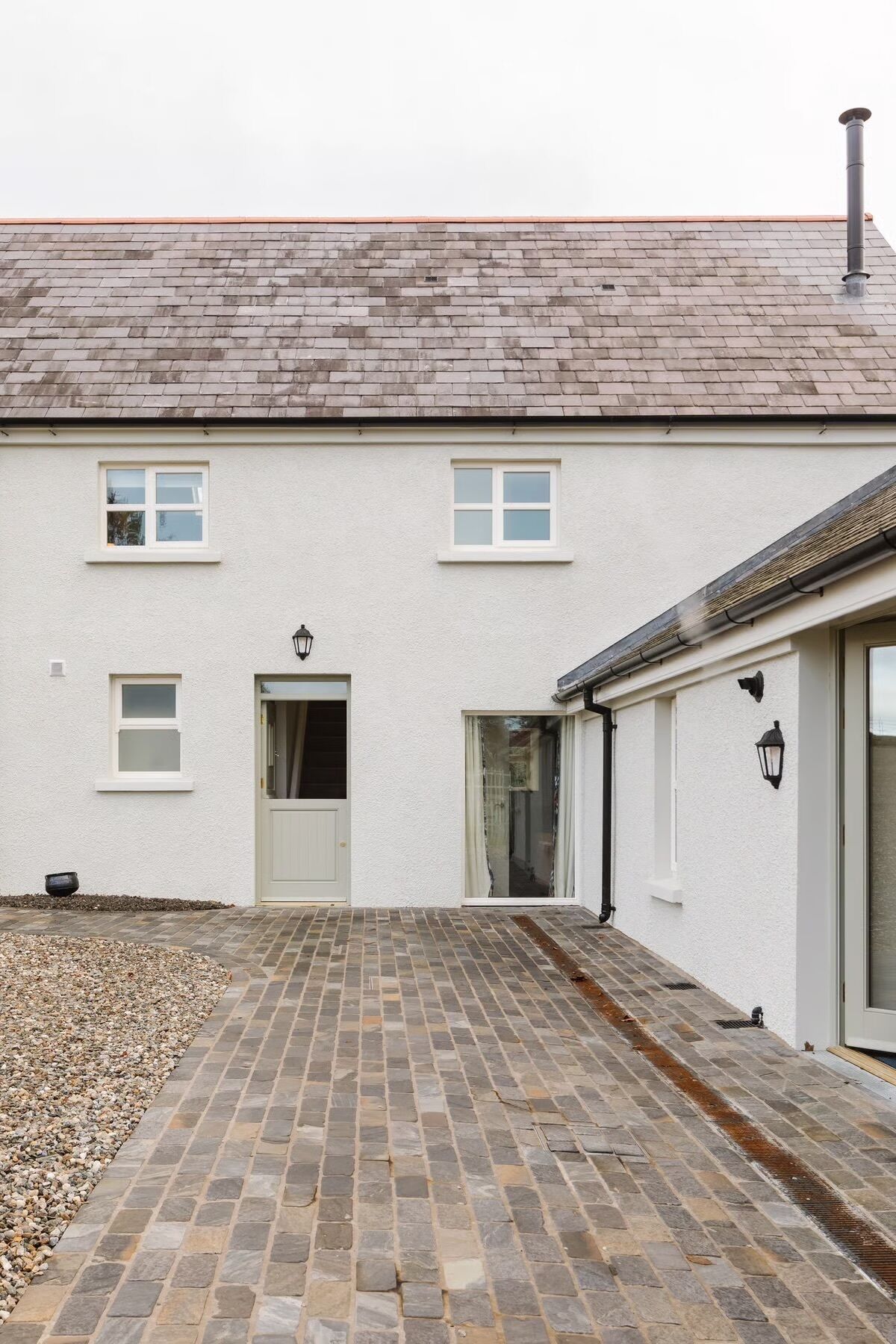 A two-story building with a tiled driveway, a door, and a window.