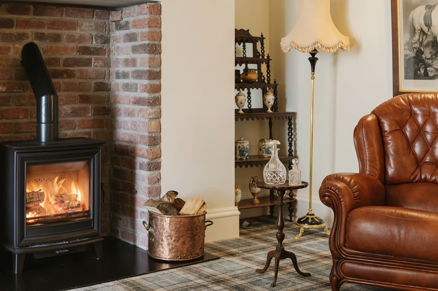 A room with a brick fireplace, a leather armchair, and a lamp.