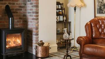 A room with a brick fireplace, a leather armchair, and a lamp.