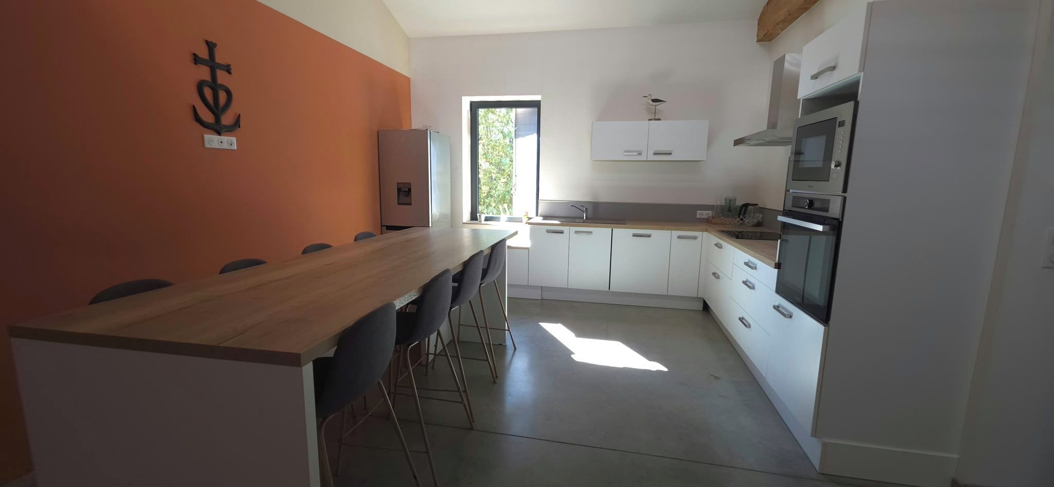 A kitchen with a wooden table and chairs, white cabinets, and a window.