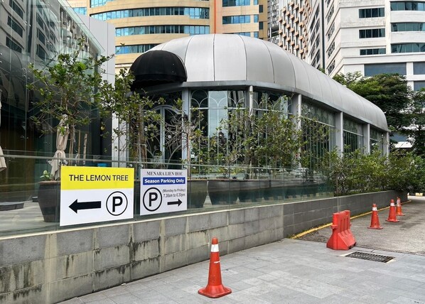 A modern building with a curved glass facade, a parking sign indicating season parking, and a sign pointing to 'The Lemon Tree.' - Lumi Tropicana - Unique Stays! (Petaling Jaya)