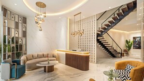 A modern interior with a reception desk, a curved staircase, and a seating area with sofas and a coffee table.