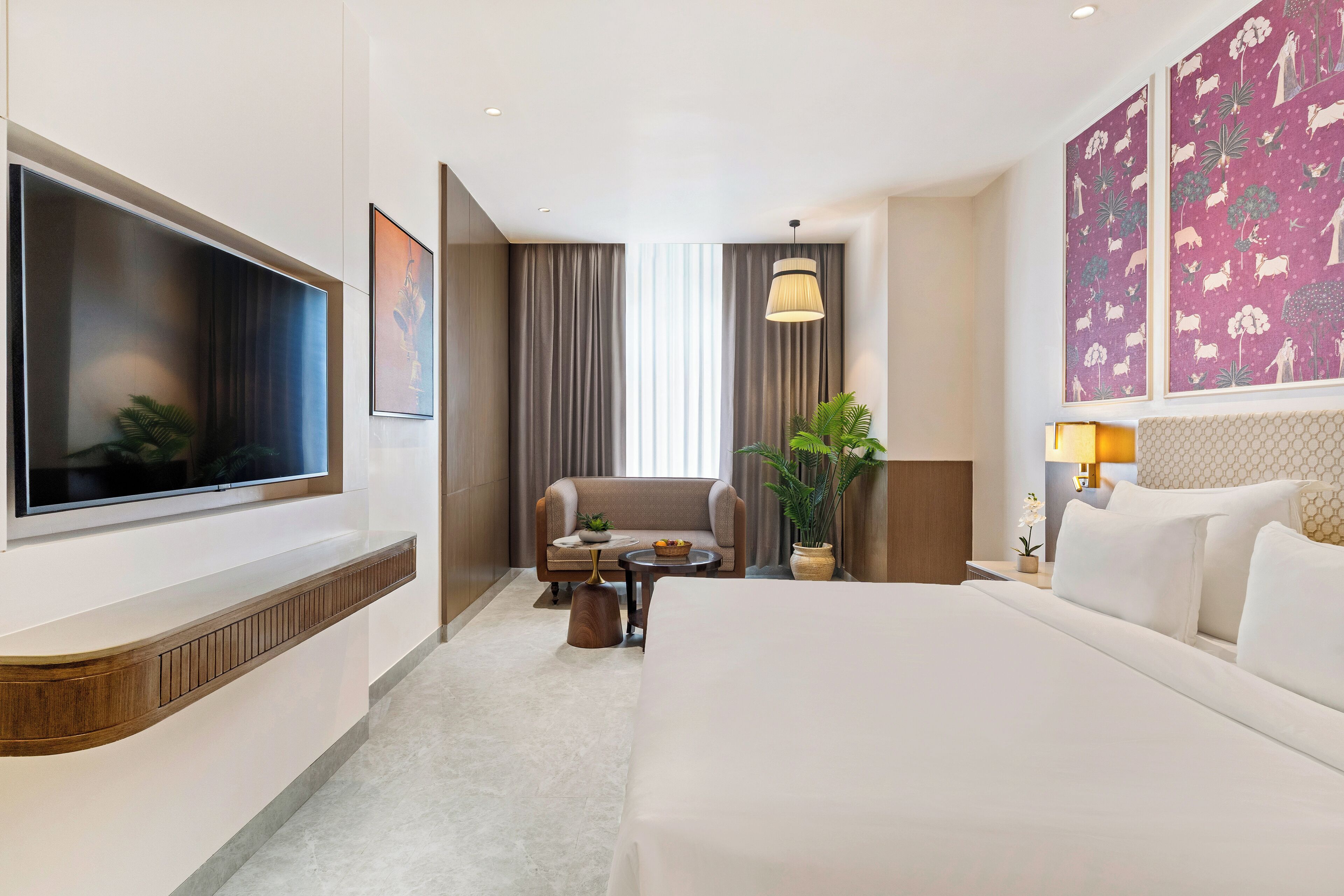Une chambre d’hôtel avec un grand lit, une télévision, un canapé, une petite table et une plante en pot.