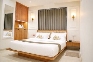 Quarto moderno com estrutura de cama de madeira, roupa de cama branca e duas mesas de cabeceira com abajures.