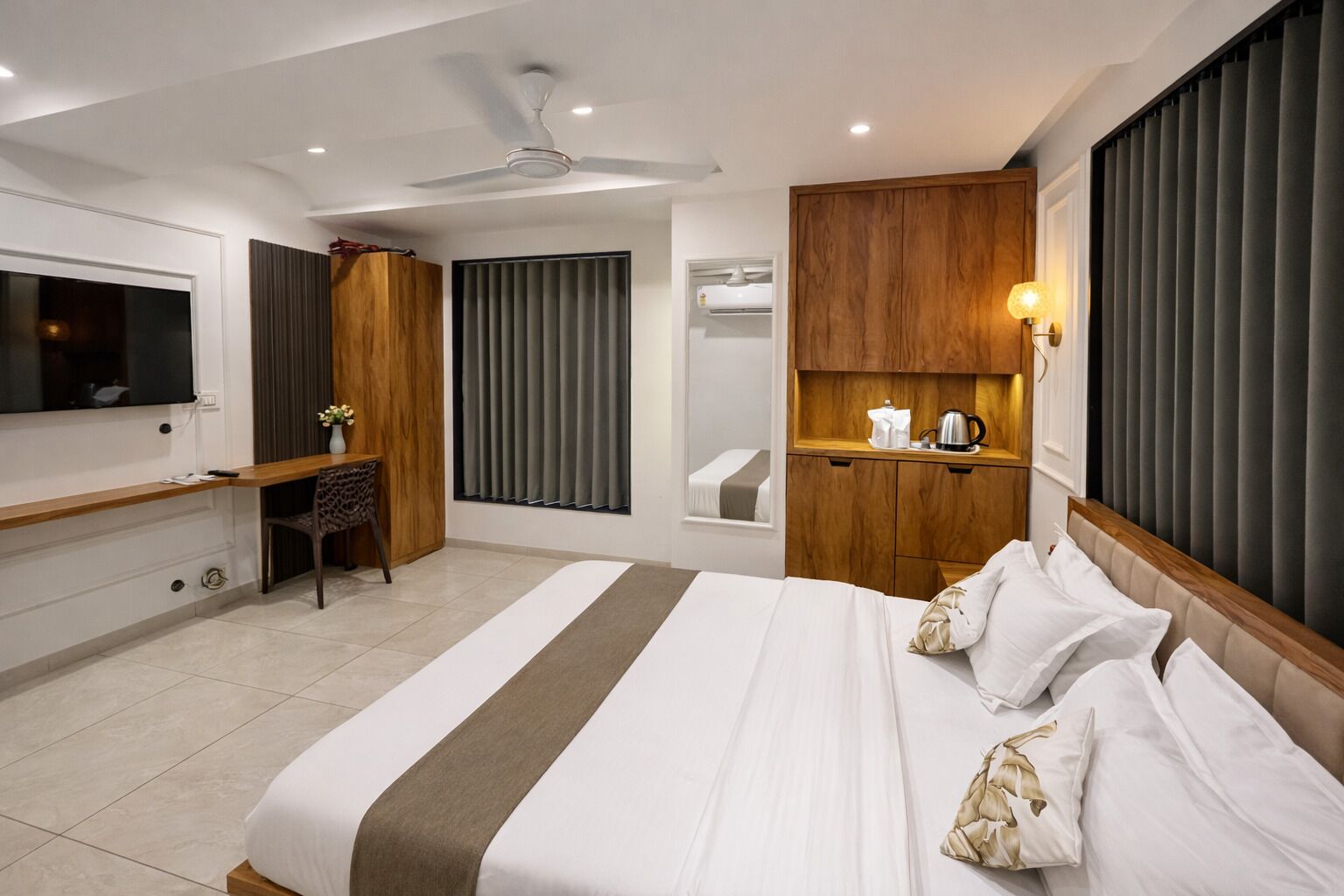 A modern hotel room with a large bed, a desk, a television, and a bathroom with a shower and toilet.