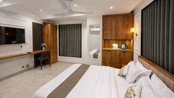 A modern hotel room with a large bed, a desk, a television, and a bathroom with a shower and toilet.