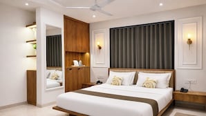 A modern bedroom with a large bed, wooden wardrobe, bedside tables, and a ceiling fan. - Hotel Raw Leaves Premium Family & Business Hotel Near Rajkot Railway Station (Rajkot)
