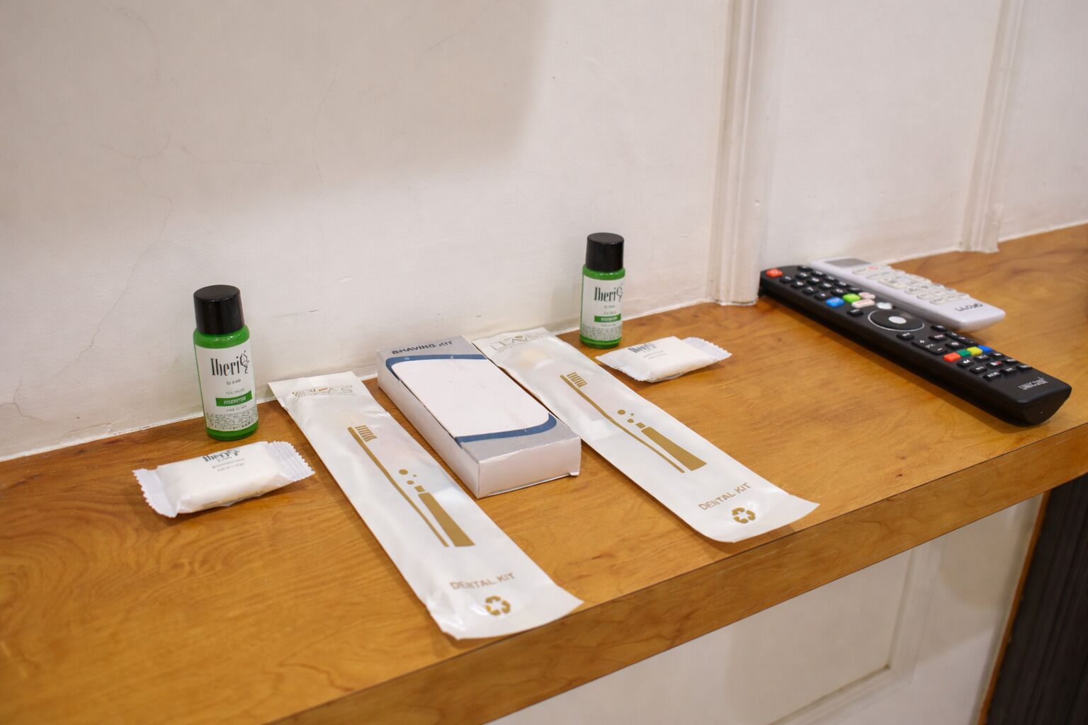Una mesa de madera con un kit dental, un control remoto y una botella de enjuague bucal.