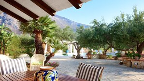An outdoor seating area with a wooden table, striped cushions, and a decorative vase.
