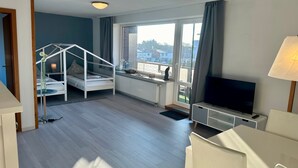 Ein modernes Zimmer mit Etagenbett, Fernseher, Schreibtisch und großen Fenstern.