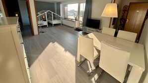Ein modernes Wohnzimmer mit einer Couch, Fernseher und Essbereich.