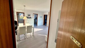 Ein geräumiges Zimmer mit Essbereich, einer Küche im Hintergrund und einer Tür mit Messinggriffen.