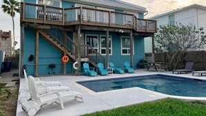 A two-story house with a balcony, a swimming pool, and outdoor seating. - Spacious - Retama Retreat - Steps from Beach! (South Padre Island)