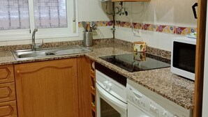 Eine Küche mit Granit Arbeitsplatten, Holzschränken, einem eingebauten Ofen, einem Geschirrspüler und einem Fenster mit Milchglas.