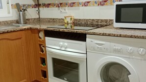 Eine Küche mit Holzausstattung, einer Mikrowelle, einem Backofen und einer Waschmaschine.