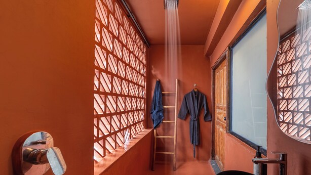 A bathroom with a shower, a sink, and a window with a lattice design. - ONEOFF X ASSI A BOUTIQUE HOMEOTEL (Varanasi)