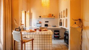 A kitchen with a tiled backsplash, a central island, and a hanging light fixture. - ONEOFF X ASSI A BOUTIQUE HOMEOTEL (Varanasi)