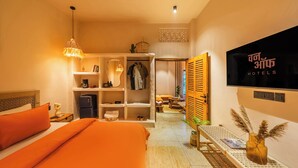 A hotel room with a bed, a wardrobe, a TV, and a seating area. - ONEOFF X ASSI A BOUTIQUE HOMEOTEL (Varanasi)