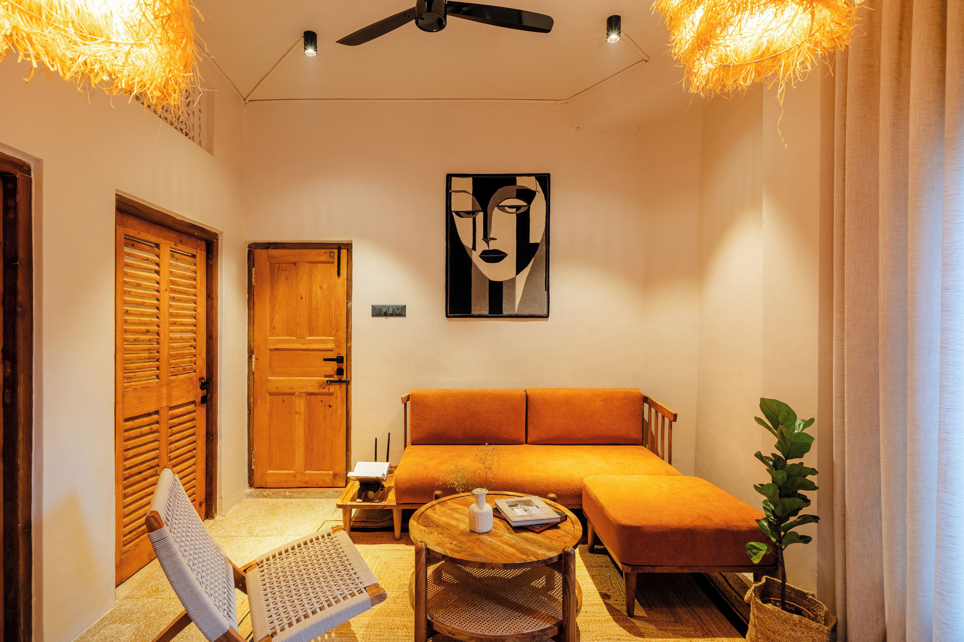 A cozy room with a sofa, a round table, a chair, a ceiling fan, and a door.