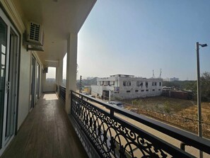 A balcony with a view of a building and a clear sky. - Dwellr Luxury Stays (Gurugram)