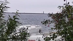 Un bateau doté d’une cabine et offrant une vue sur la mer et un phare situé au loin.