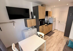 A compact kitchen with a flat-screen TV, wooden cabinets, a microwave, and a refrigerator. - Les Soldanelles Le Mont Dore 12 pers (Mont-Dore)