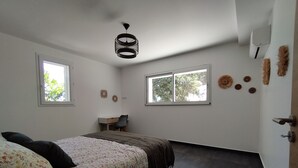 Un dormitorio con cama, dos ventanas, un escritorio y una lámpara en el techo.