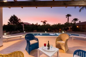 A poolside area with wicker chairs and a table with a bottle and glasses. - Villa Le Sterlizie con Piscina Privata (Castellammare del Golfo)