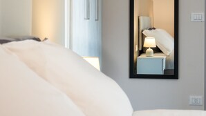Ett hotellrum med en säng, ett nattduksbord med en lampa, en spegel och en garderob.