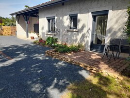 Una casa con camino de grava, borde de piedra y un patio con una silla.