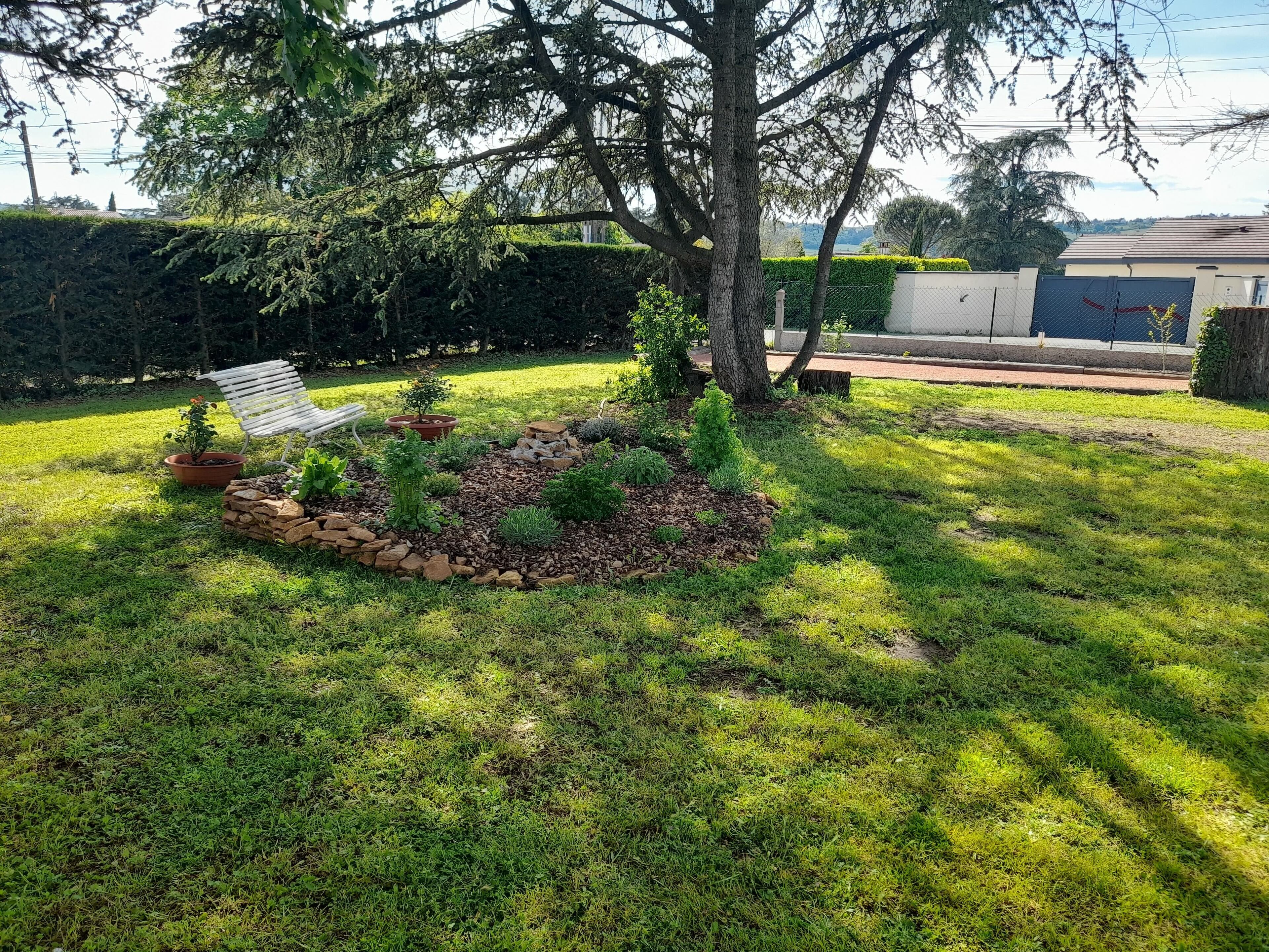 A well-maintained garden with a variety of plants and a white chair.