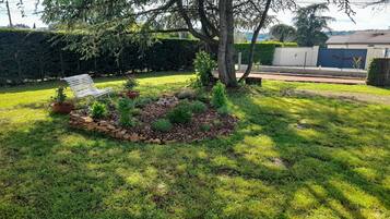 A well-maintained garden with a variety of plants and a white chair.